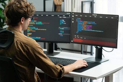 Person sitting in front of two screens working in an IDE